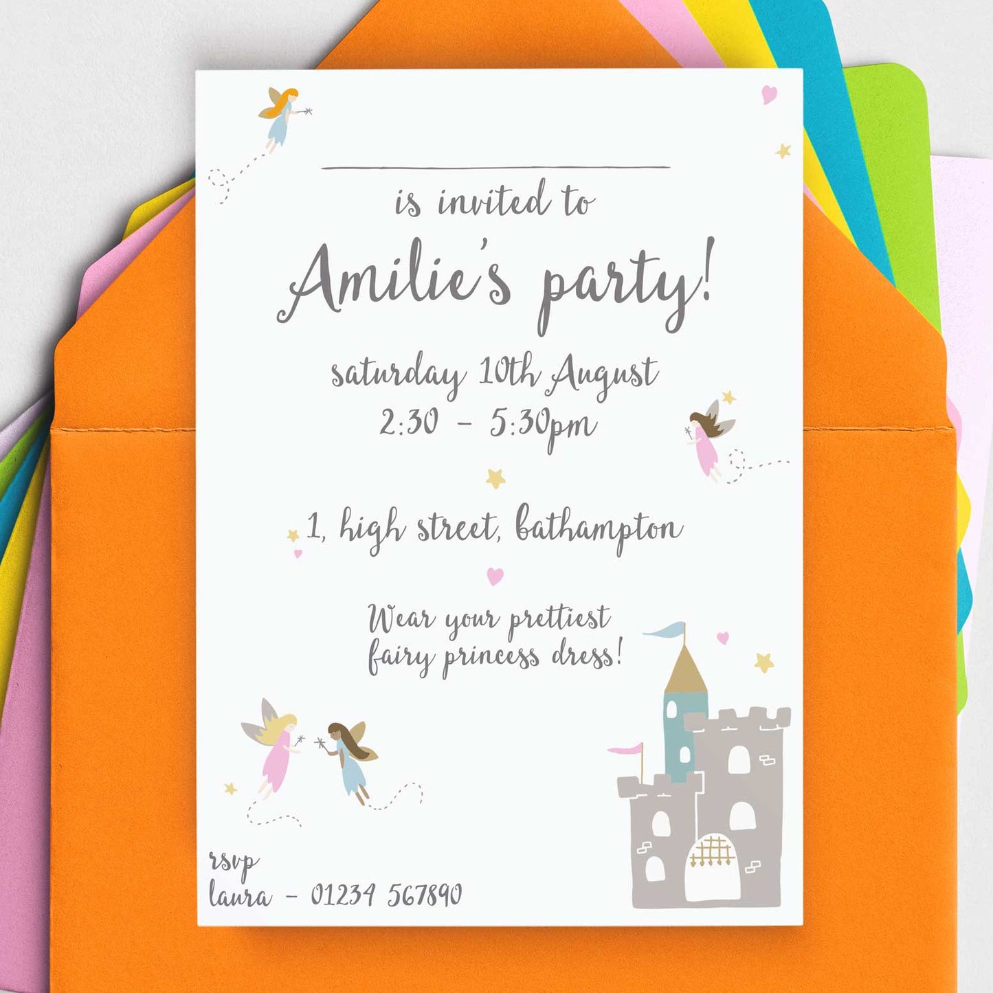 A flat lay of printed party invitations with a fairy castle illustration, accompanied by colored envelopes.