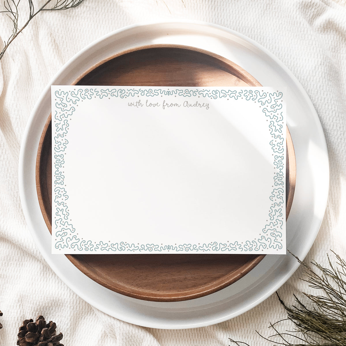 An A6 white stationery card with a duck egg blue decorative border and gold script text at the top.