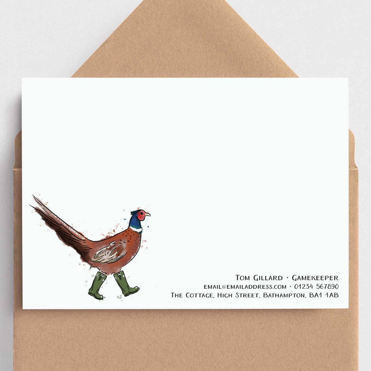 A white stationery card with a whimsical illustration of a pheasant walking in green boots and black printed contact details, shown with a brown kraft envelope on a light gray background.